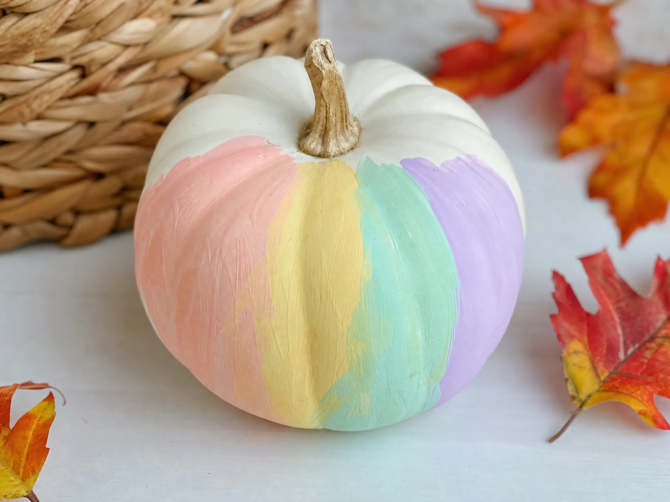White mini pumpkin painted with soft pastel rainbow bands