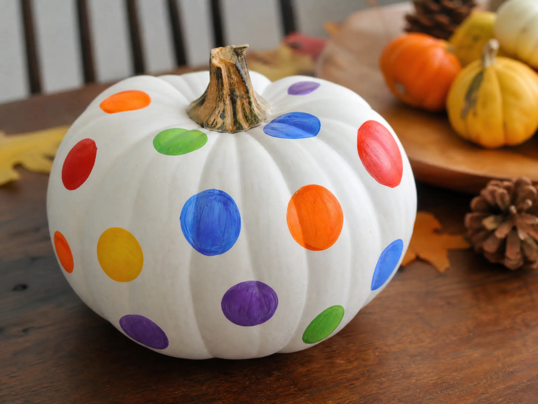 White pumpkin decorated with colorful rainbow polka dots