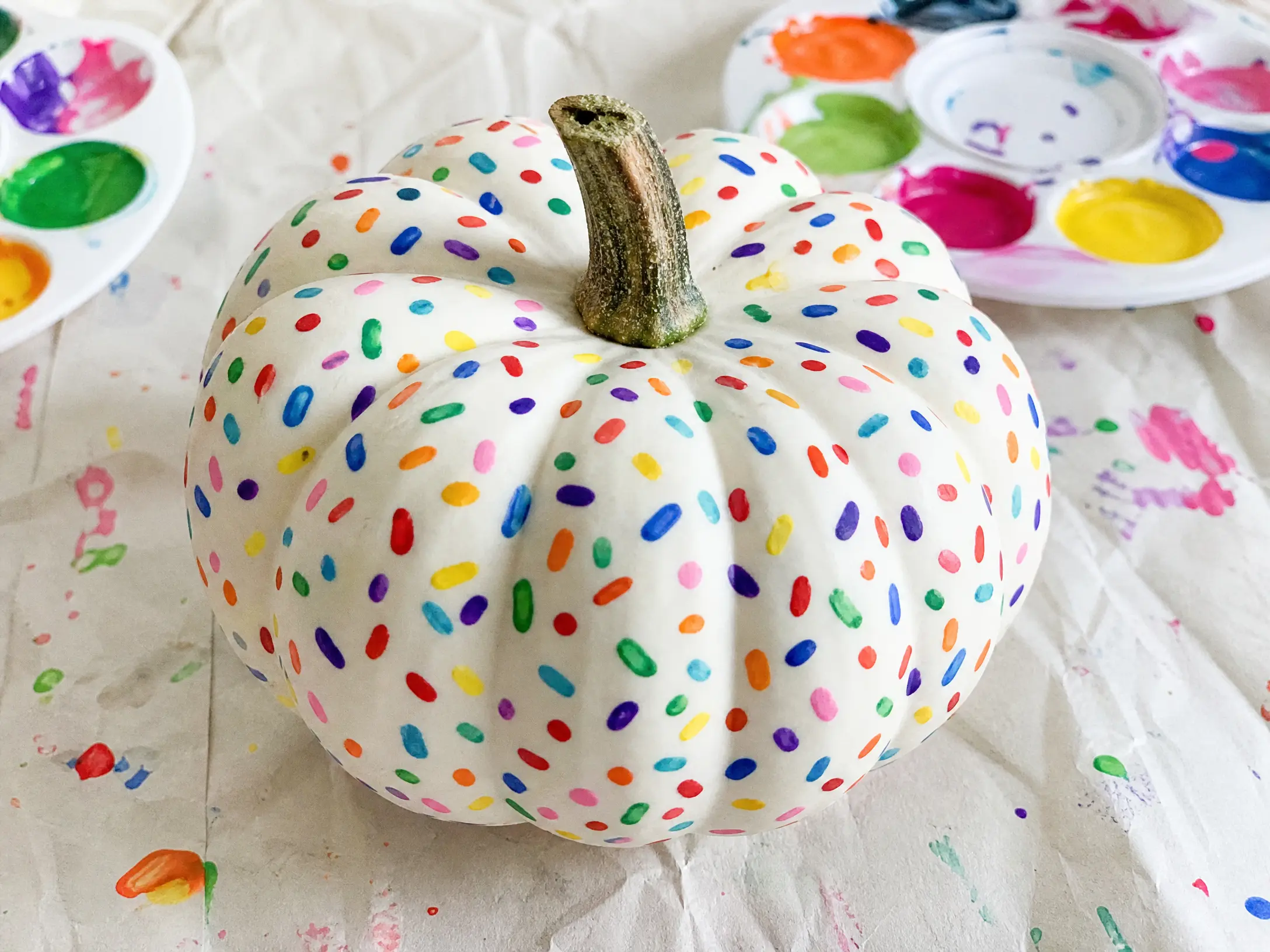 White mini pumpkin covered with tiny rainbow confetti marks