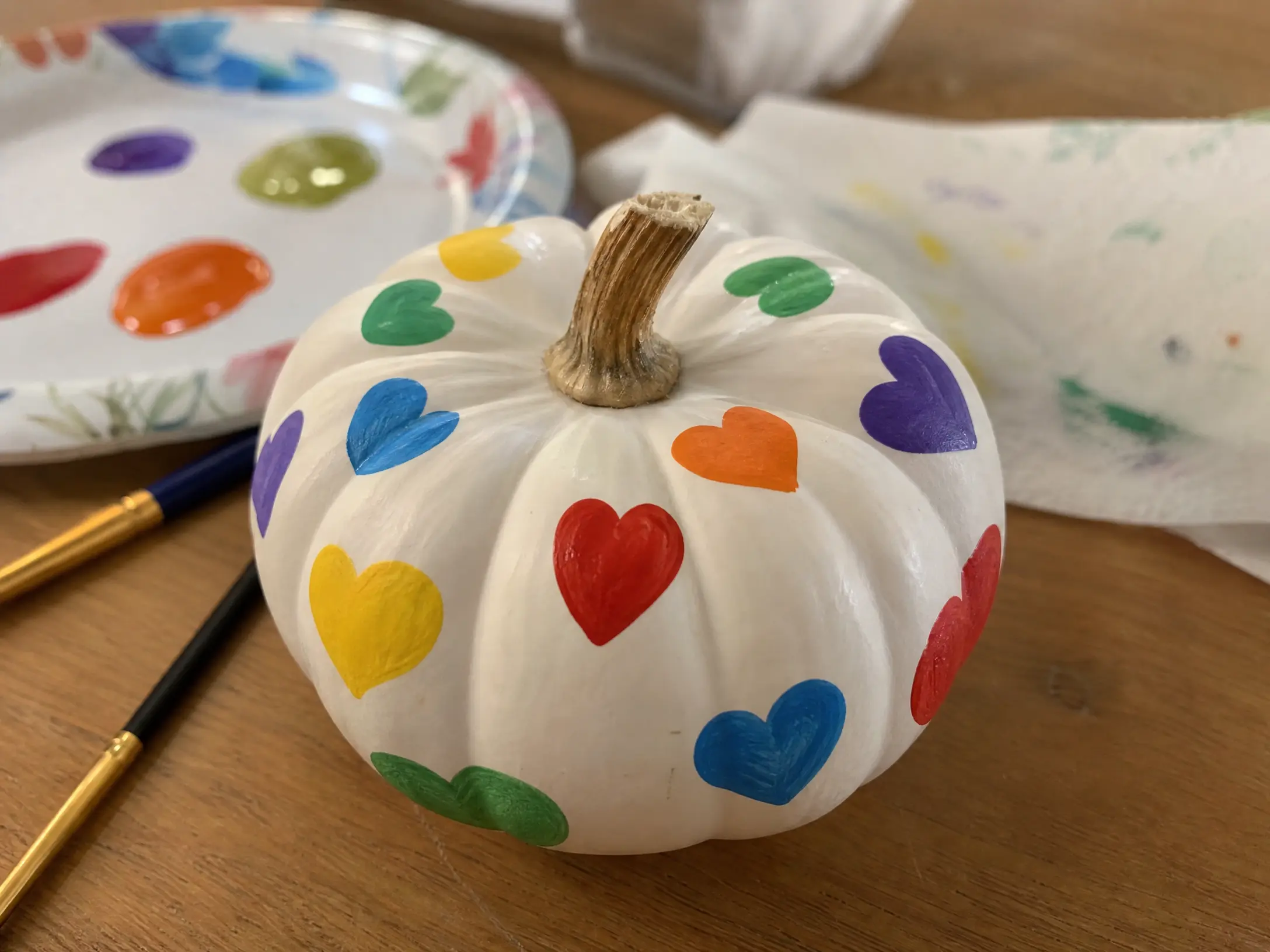 White mini pumpkin painted with colorful rainbow hearts