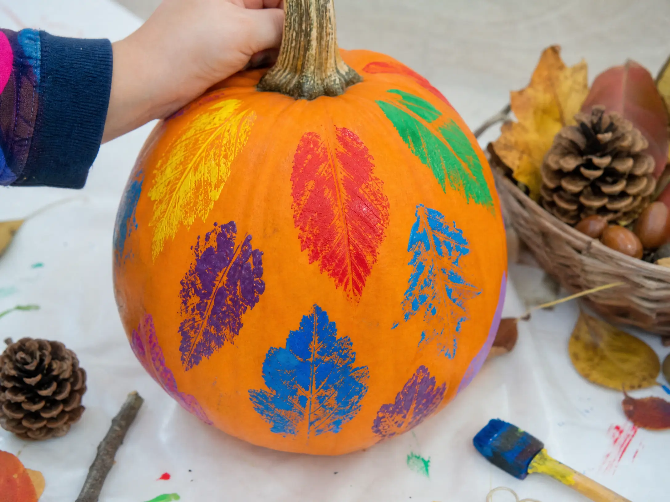 Orange pumpkin decorated with colorful rainbow leaf-print shapes