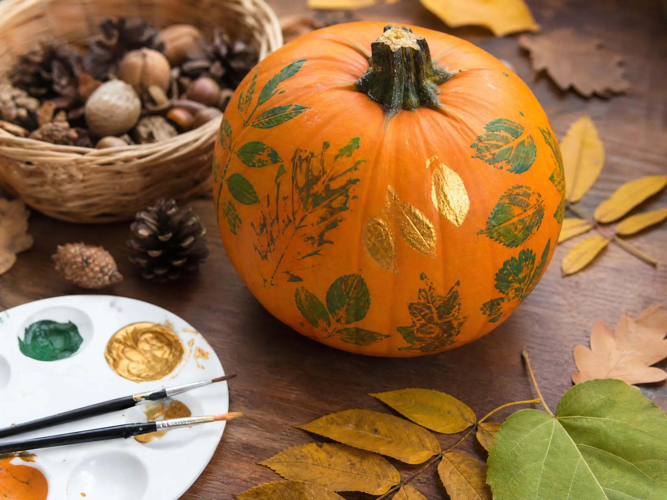 Orange pumpkin decorated with green and gold leaf-print shapes