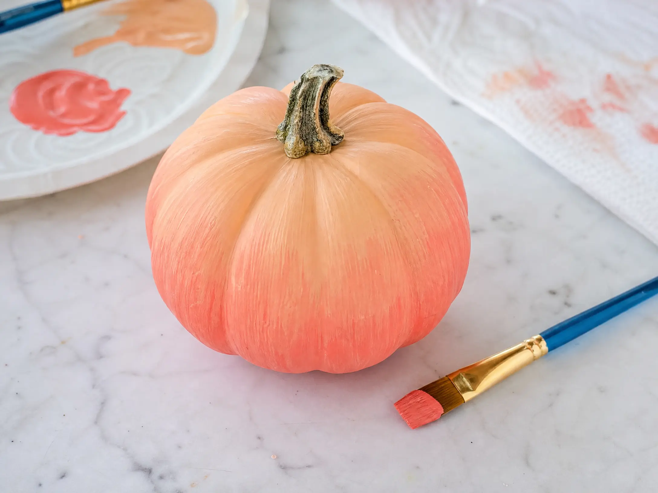 Mini pumpkin painted in a peach-to-coral ombre gradient