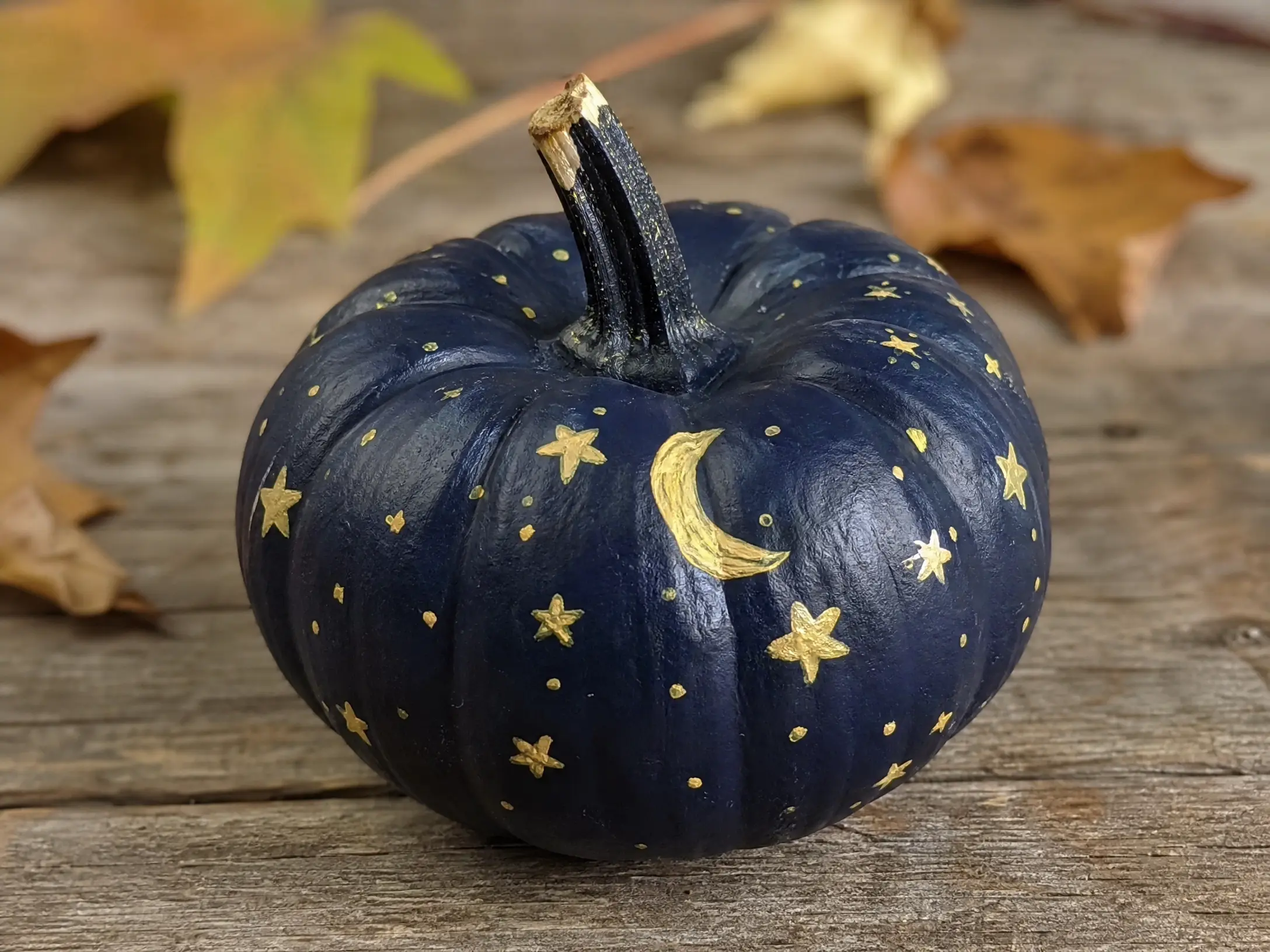 Deep navy pumpkin painted with gold stars and a crescent moon