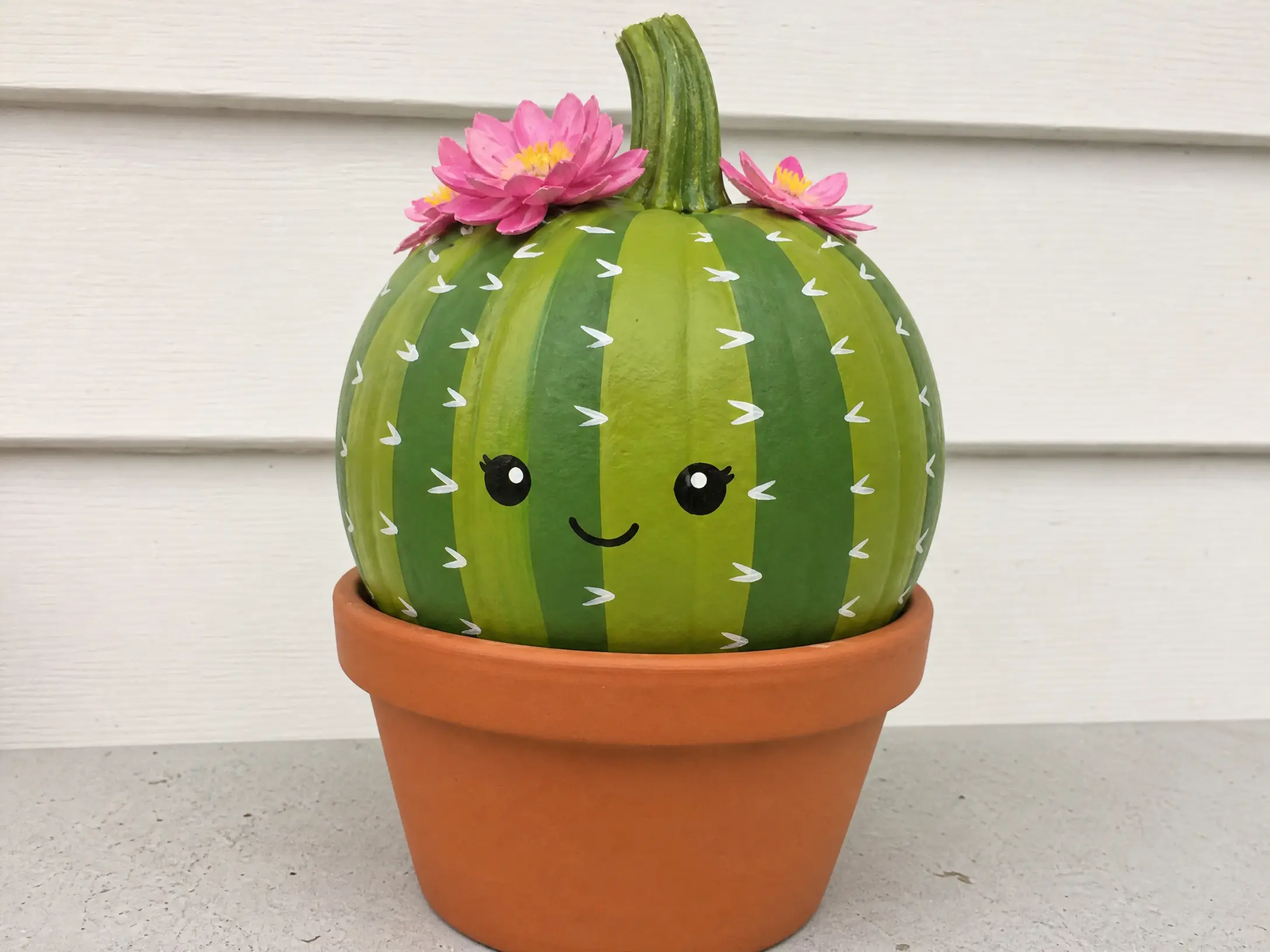 Green cactus-style pumpkin with tiny pink flowers