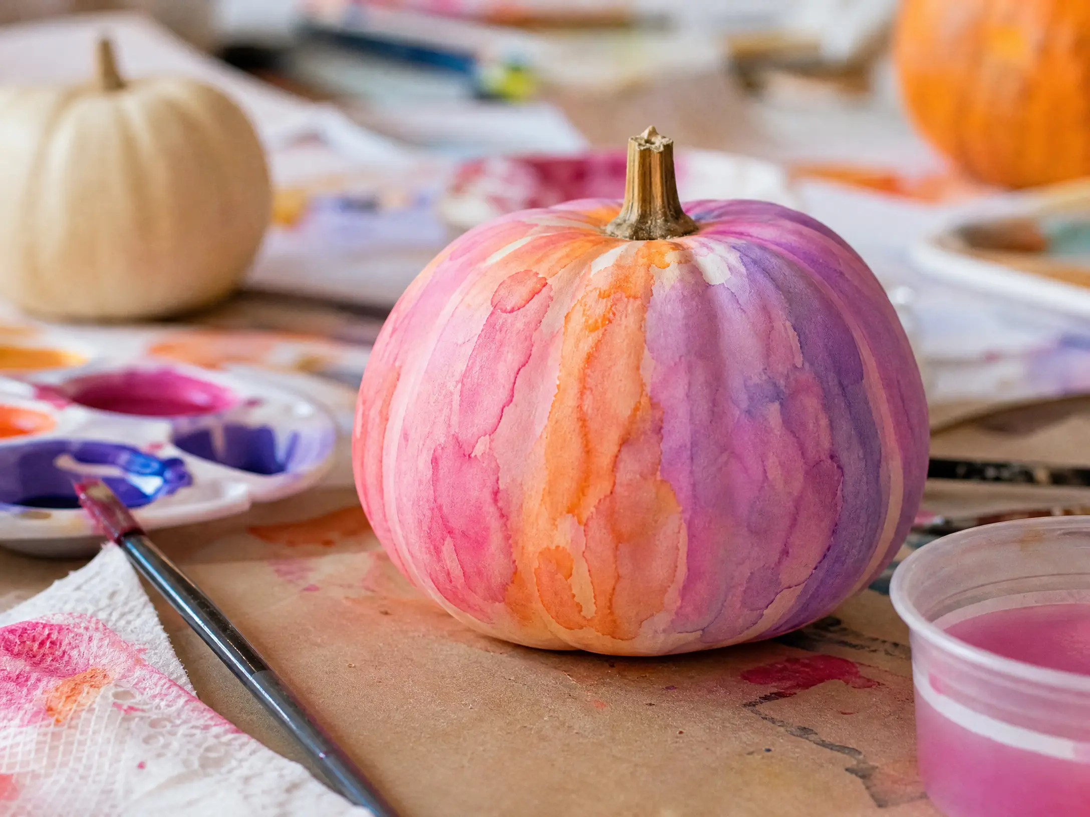 Mini pumpkin painted with translucent pink, orange, and purple washes