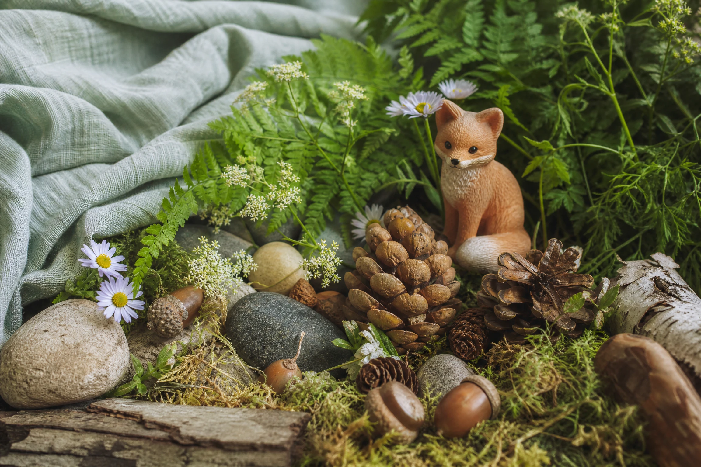 Fern leaves, wildflowers, pinecones, acorns, and smooth stones in a natural still life